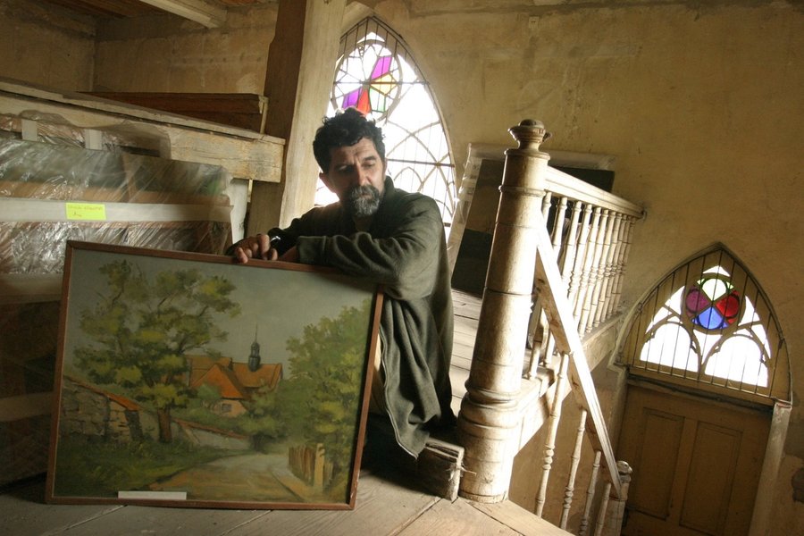 Antoni Szulc z jednym ze swoich pejzaży w starej ewangelickiej kaplicy w Śmiglu. Fot. Maciej Mosur / PROJEKT PKS 050505